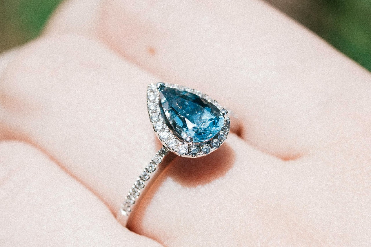 A pear-cut topaz set in a halo cut engagement ring.